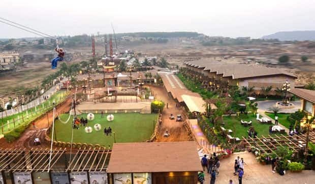 Aerial view of a camping site featuring a zip line, grassy areas, and several structures for recreational activities.