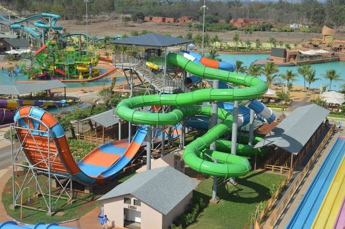 Colorful water slides in a water park featuring green and orange tubing structures and a multi-level platform.