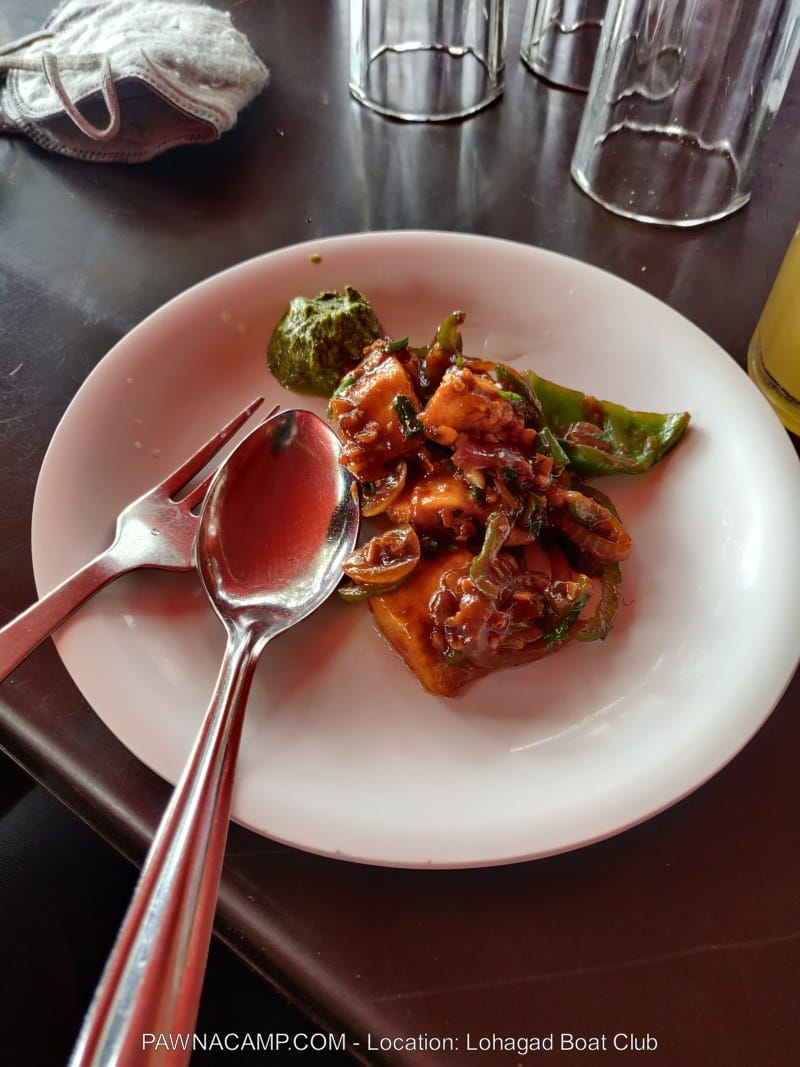 A plate containing a portion of chicken with vegetables, garnished with green sauce and served with cutlery.