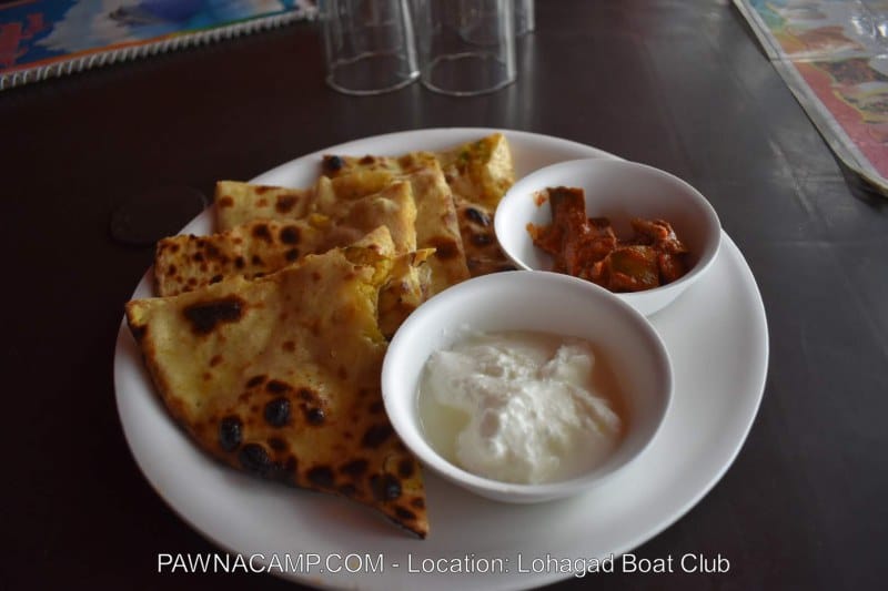 A plate containing Indian flatbreads served with yogurt and a spicy side dish in small bowls.