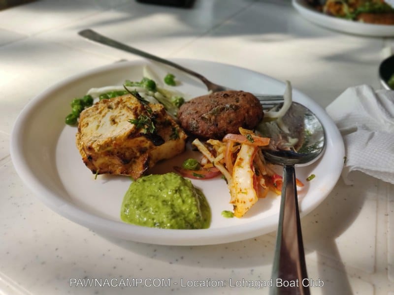 A plate containing grilled paneer, a vegetable patty, salad, and green chutney served at Lohagad Boat Club.